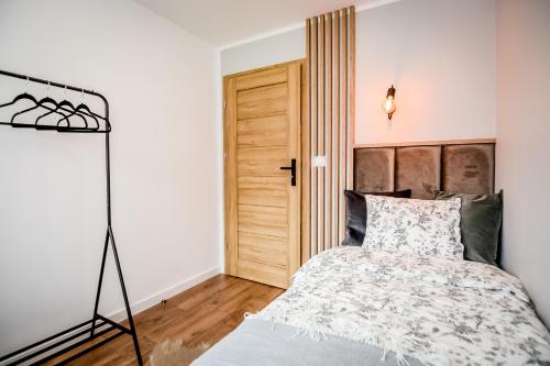 a bedroom with a bed and a wooden floor at Podtatrzańskie Apartamenty in Nowy Targ