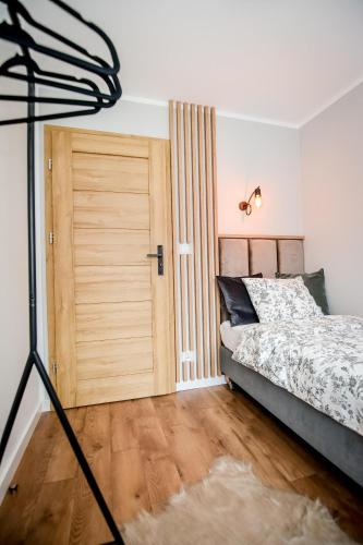 a bedroom with a bed and a wooden door at Podtatrzańskie Apartamenty in Nowy Targ