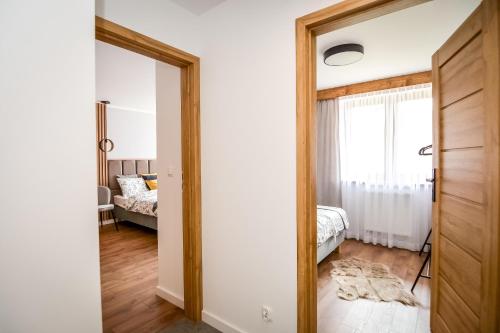 a bedroom with a door open to a bedroom with a bed at Podtatrzańskie Apartamenty in Nowy Targ