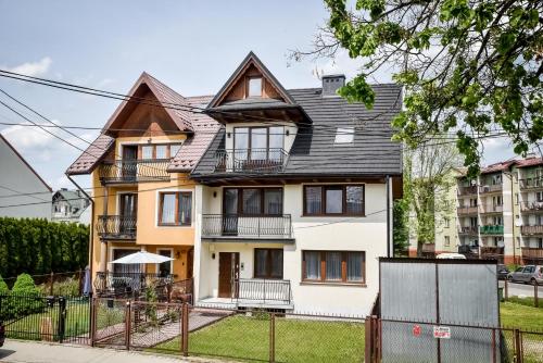 a large white house with a black roof at Podtatrzańskie Apartamenty in Nowy Targ