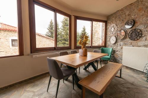 d'une salle à manger avec une table en bois, des chaises et des fenêtres. dans l'établissement Παραδοσιακός Ξενώνας Βαμβακούς, à Vamvakoú