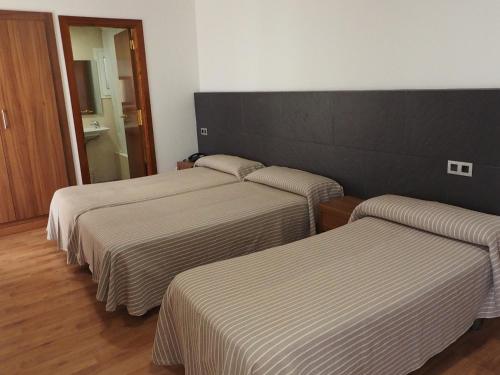 3 Betten in einem Hotelzimmer mit gestreifter Bettwäsche in der Unterkunft Hotel la Palmera & Spa in Lloret de Mar