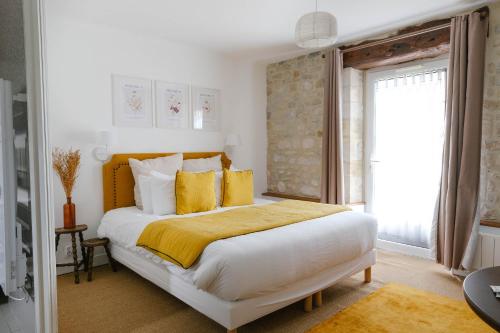 a bedroom with a large white bed with yellow pillows at Ferme des Goupillières in Maisons