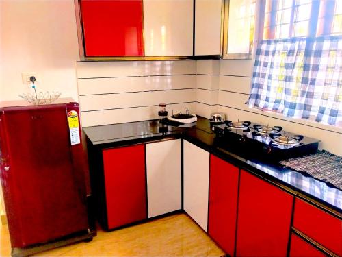 eine Küche mit roten Schränken und einem roten Kühlschrank in der Unterkunft Casa Maria Mystica apartments, Mananthavady, Wayanad in Mānantoddy