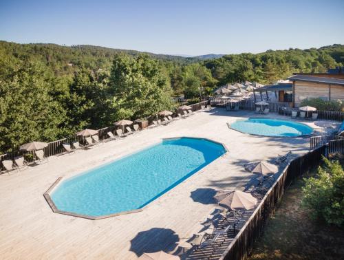 - une vue sur la piscine bordée de parasols dans l'établissement Village Huttopia Sud Ardèche, à Vagnas