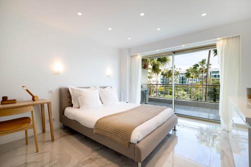 een slaapkamer met een bed en een groot raam bij Agence des Résidences - Appartements privés du 45 CROISETTE- Prestige in Cannes