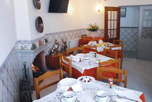 a dining room with tables and chairs and a fireplace at Vale a Pena - Alojamento Local in Trancoso
