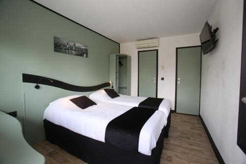 a bedroom with a large bed with white and black sheets at Enzo Hotels Chartres Mainvilliers by Kyriad Direct in Chartres