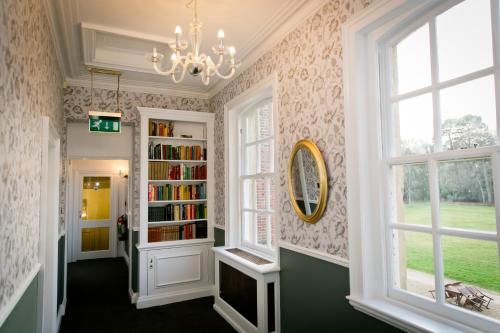 フックにあるWarbrook House Heritage Hotelの本棚とシャンデリアのある廊下