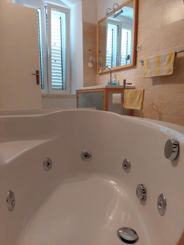 a white bath tub in a bathroom with a mirror at Apartments Batala in Dubrovnik
