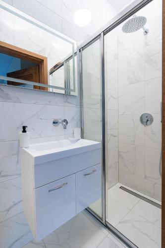 a white bathroom with a sink and a shower at Apartamenty Olimpijska by RENT4YOU in Olsztyn