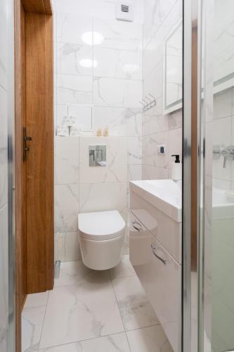 a white bathroom with a toilet and a sink at Apartamenty Olimpijska by RENT4YOU in Olsztyn