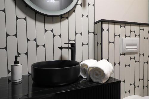 a bathroom with a black sink and black and white wallpaper at La Villa Ponsin in Cognac
