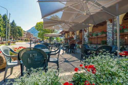 an outdoor cafe with chairs and tables and an umbrella at B&B San Sebastiano in Vernante