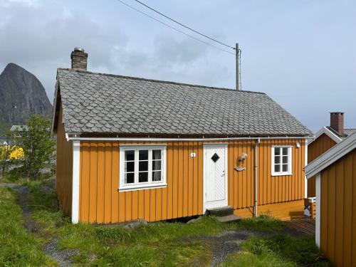 a small orange house with a white door at Sakrisøy Rorbuer in Reine