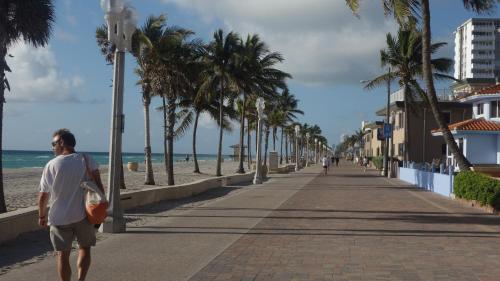a man walking down a sidewalk next to the beach at Ocean Drive Villas in Hollywood