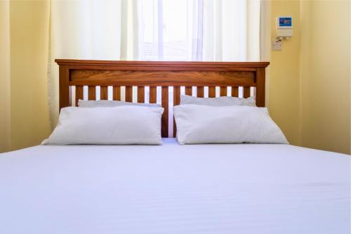 a bed with two white pillows and a window at City Gem Near Tanzanite Bridge! in Dar es Salaam