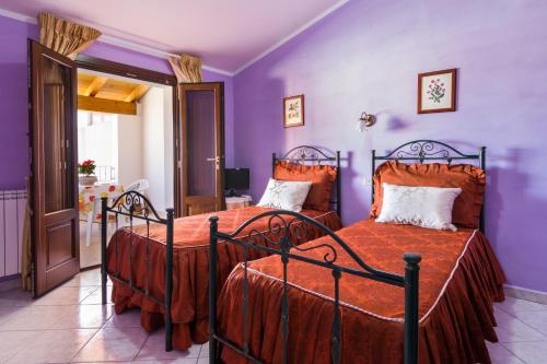 two beds in a bedroom with purple walls at Casa Titti in Càbras