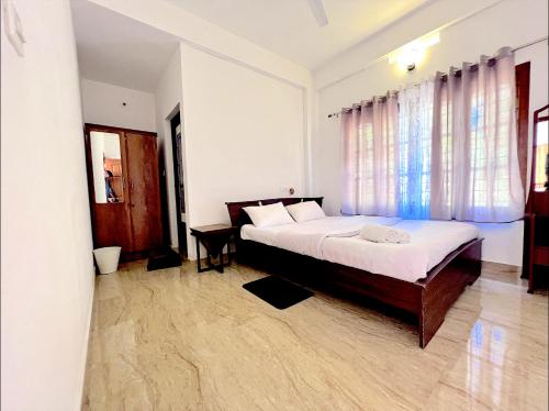 ein Schlafzimmer mit einem großen Bett und einem Fenster in der Unterkunft Casa Maria Mystica apartments, Mananthavady, Wayanad in Mānantoddy