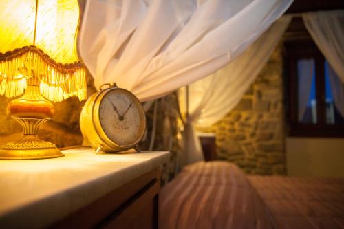 a clock sitting on a dresser next to a bed at Canto del Fiume in Ortignano Raggiolo