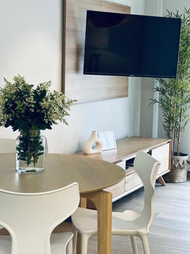 a dining room with a table and chairs and a tv at Apartamentos Noja Playa in Noja