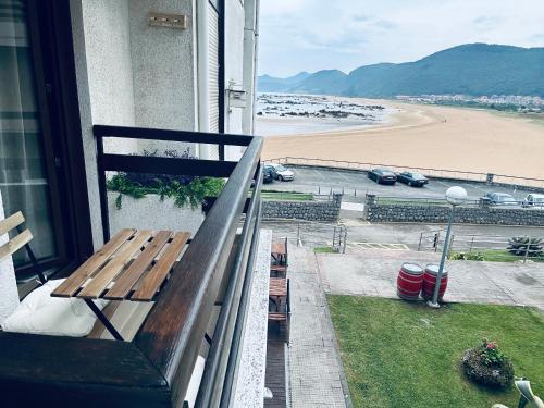 a bench on a balcony with a view of a beach at Apartamentos Noja Playa in Noja