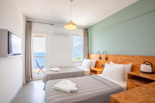 two beds in a hotel room with a view of the ocean at Mavilim Hotel in Kas
