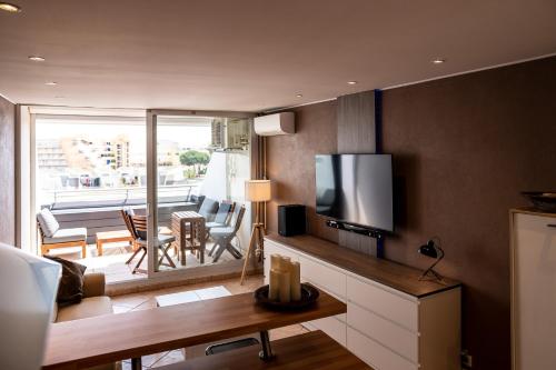 ein Wohnzimmer mit einem TV und ein Wohnzimmer mit einem Tisch in der Unterkunft Cap d'Agde Suit'Appart 42m2 T2 Village Naturiste in Cap d'Agde
