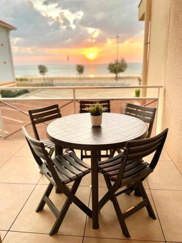 une table avec des chaises et une plante en pot sur un balcon dans l'établissement Vue océan, superbe appartement, à Soulac-sur-Mer