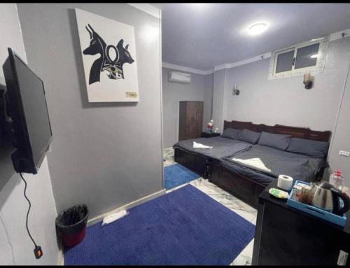een kleine kamer met een bed en een televisie bij City pyramids inn in Caïro