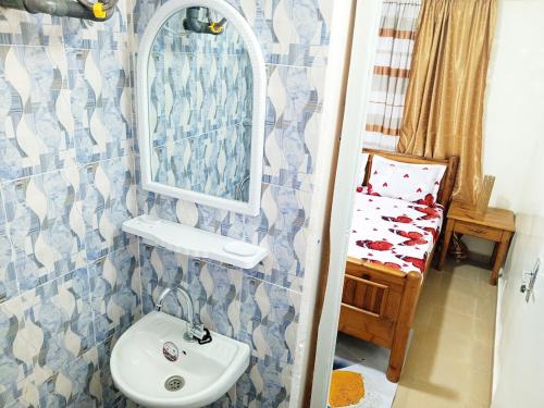 baño con lavabo, espejo y cama en RÉSIDENCE NGUARY en Dakar
