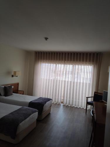 a hotel room with two beds and a large window at Hotel dos Loios in Santa Maria da Feira
