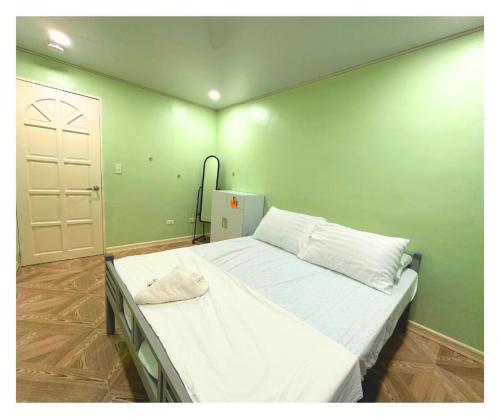 un grande letto in una stanza con parete verde di Velasquez Farmhouse/Affordable Holiday Rental Near Hundred Islands 