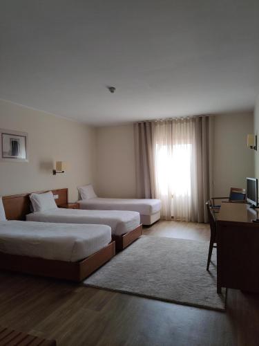 a hotel room with two beds and a window at Hotel dos Loios in Santa Maria da Feira