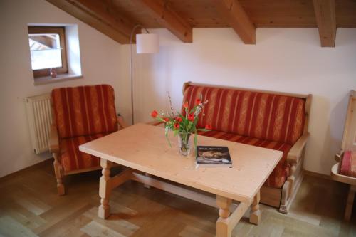 a table with a vase of flowers and two chairs at Ferienwohnungen Kir Royal in Krün