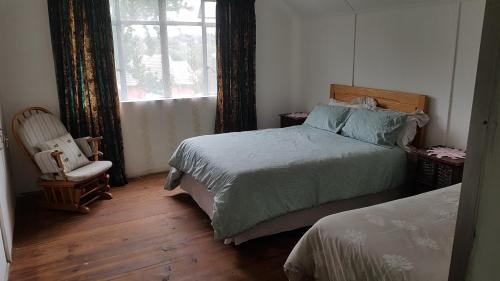 a bedroom with two beds and a chair and a window at Crafty Coal Stove in Pietermaritzburg