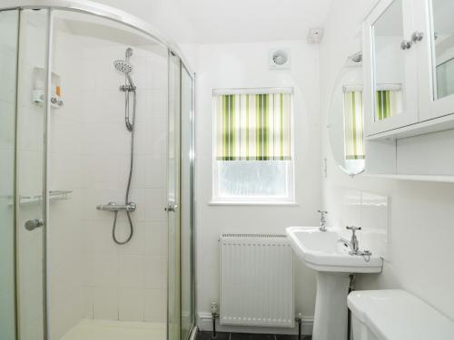 Un baño blanco con ducha y lavabo. en Spinners House, en Dartmouth