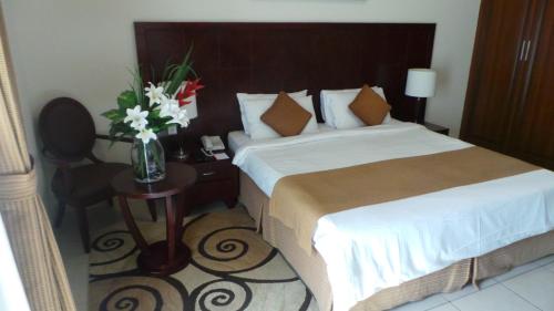 a bedroom with a bed and a table with a vase of flowers at Akas-Inn Hotel Apartment in Dubai