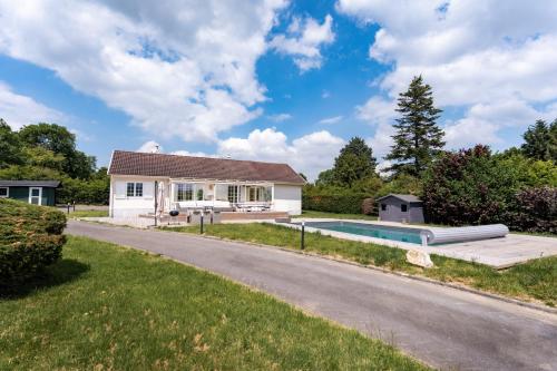 a house with a swimming pool next to a driveway at Property with heated pool near Deauville in Saint-Étienne-la-Thillaye