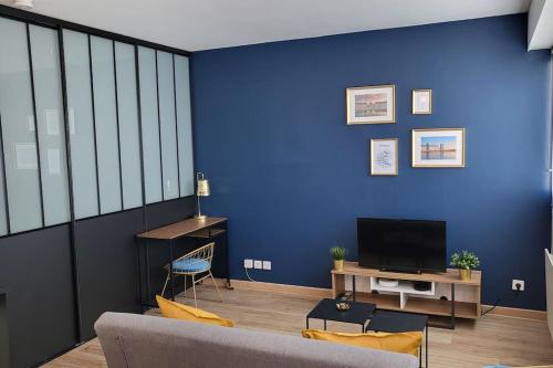 a living room with a blue wall and a tv at La Suite de Lily in Talence