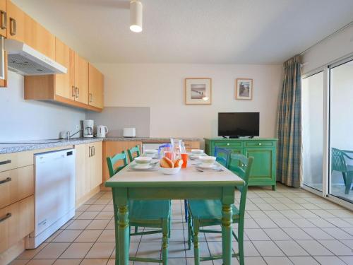 kuchnia ze stołem z krzesłami i telewizorem w obiekcie Apartment Village Cheval Spa Résidences-5 by Interhome w mieście Lacanau-Océan
