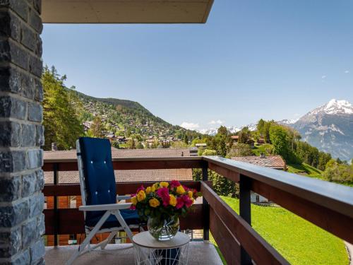 een blauwe stoel en een vaas met bloemen op een balkon bij Apartment Quille du Diable 44 by Interhome in Nendaz