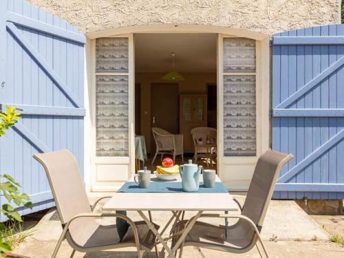 une table et des chaises sur une terrasse avec portes bleues dans l'établissement Studio L'Ayguade-2 by Interhome, à Hyères