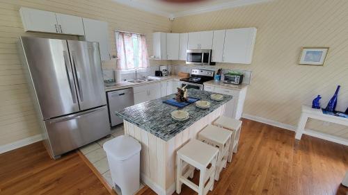 a kitchen with a refrigerator and a counter with stools at 114 Sandbar, Private Pool, Short Walk to Beach in Duck