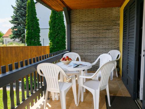 une terrasse couverte avec des chaises blanches et une table avec des fruits. dans l'établissement Holiday Home Hibiscus by Interhome, à Balatonkeresztúr