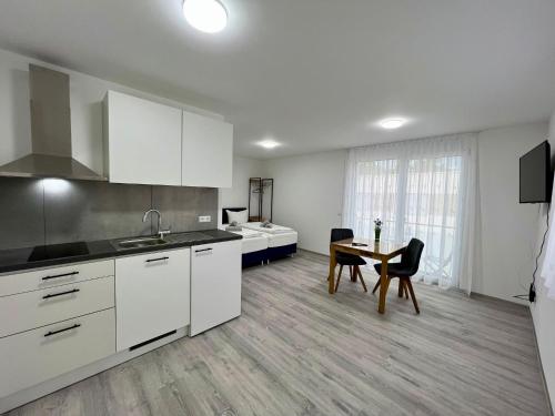 a kitchen with white cabinets and a table with chairs at GrenzApartments in Bietingen