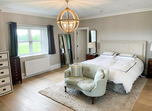 a bedroom with a bed and a chair and a chandelier at Cluain Ard Holiday Home 
