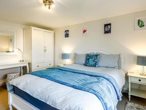 a bedroom with a bed with a blue blanket on it at Apartment Horizons by Interhome in Ilfracombe