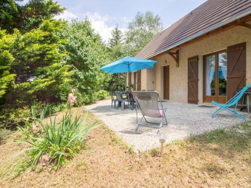 a patio with a table and a blue umbrella at Holiday Home La Châtaigneraie by Interhome in Aubazines