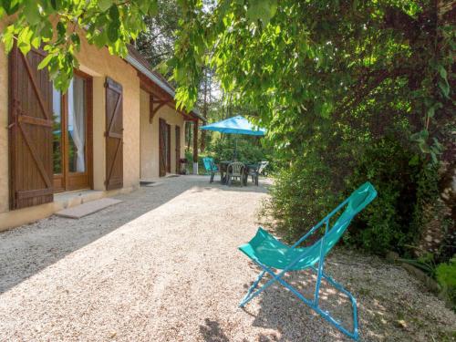 a green chair sitting next to a house with an umbrella at Holiday Home La Châtaigneraie by Interhome in Aubazines